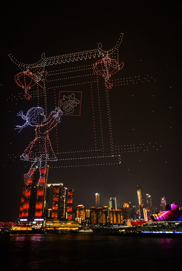 En drönarljusshow bildar ett tempel och en traditionell figur över Chongqings stadssiluett.