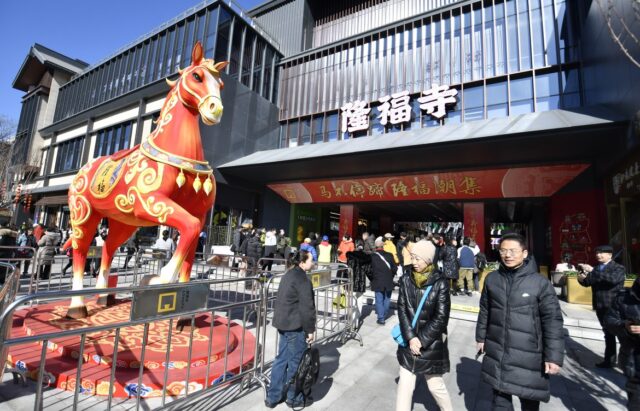 Besökare vid en stor röd hästskulptur utanför Longfusi-templet i Peking under vårfesten.