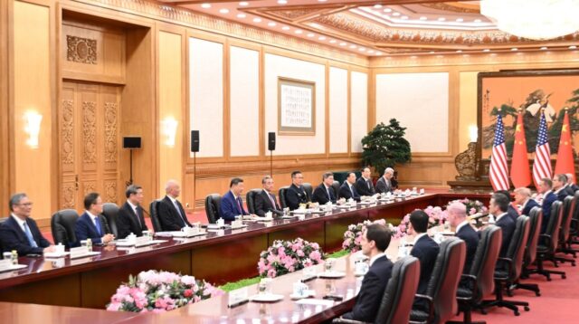 Amerikanska och kinesiska delegationer sitter mittemot varandra vid ett mötesbord i Peking.