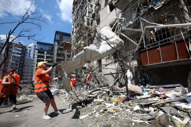 Kommunalarbetare röjer vid en skadad byggnad efter ett robotnedslag i Kiev den 2 juli 2026.