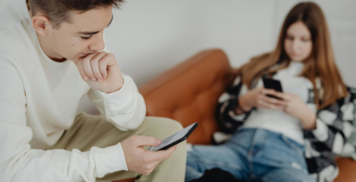 Två ungdomar sitter med mobiltelefoner