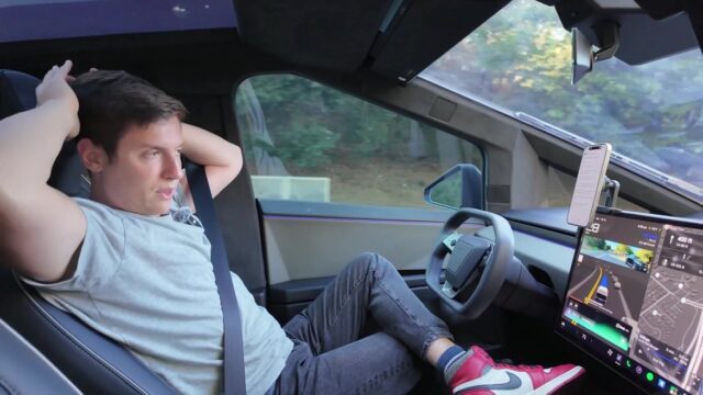Alex Finn sitter i en Tesla med händerna bakom nacken och fötterna framåt.