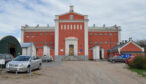 Den röda huvudbyggnaden vid Kristianstadsanstalten med parkerade bilar på gården.