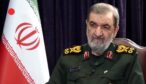 Mohsen Rezaei i militäruniform framför den iranska flaggan under en tv-intervju.