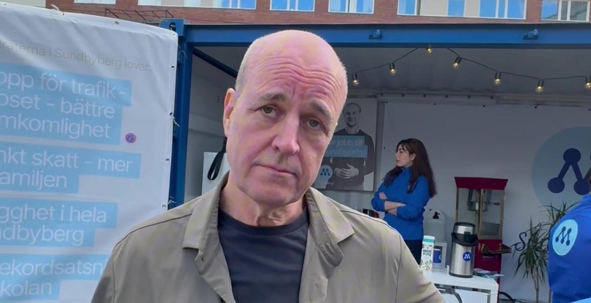 Fredrik Reinfeldt vid en blå valstuga med Moderaternas logotyp.