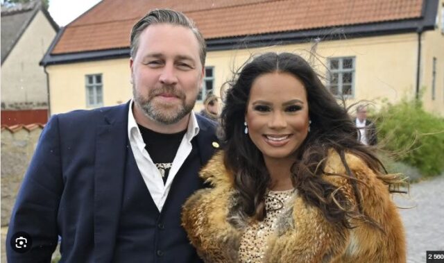 Mattias Karlsson och hans maka fotograferade utomhus framför en gul byggnad.