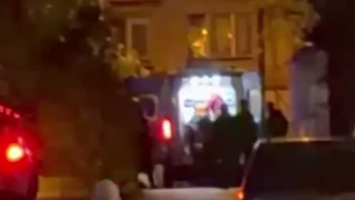 Mörk och oskarp nattbild med personer och fordon framför en upplyst entré vid rekryteringscentret i Kiev.