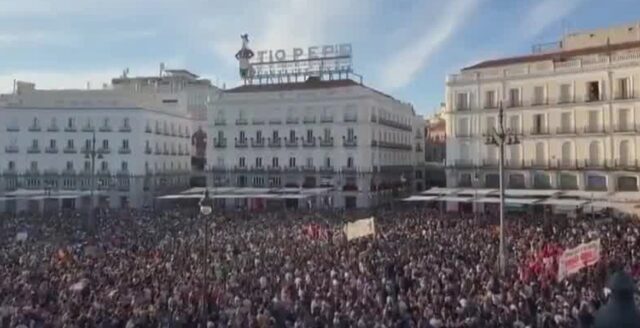 Folkmassa med banderoller på Puerta del Sol i Madrid