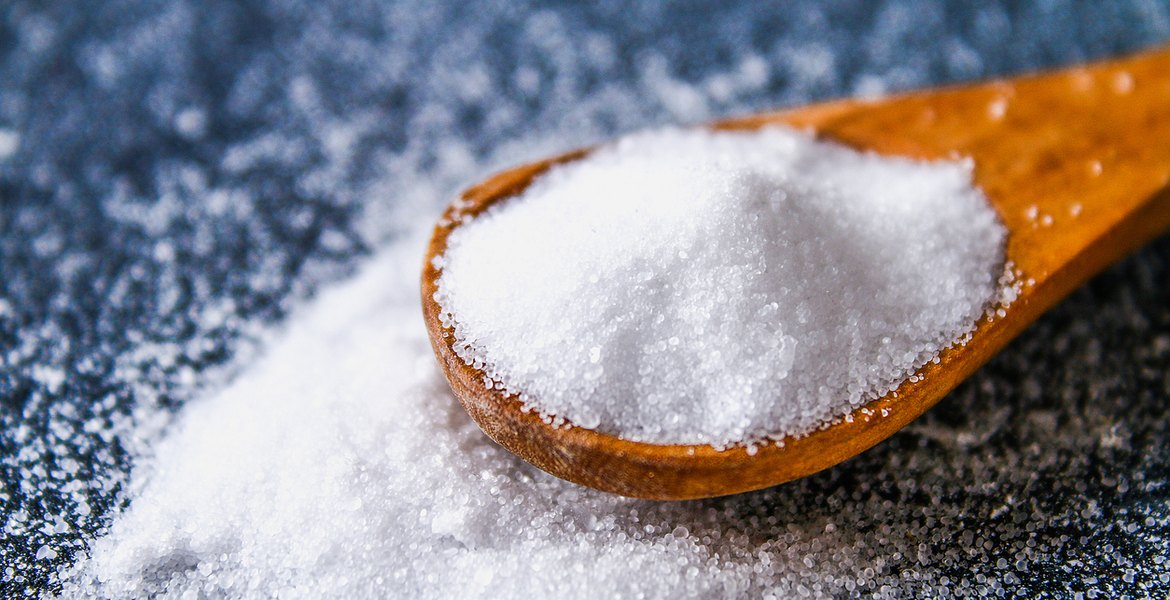 Träsked fylld med vitt salt.