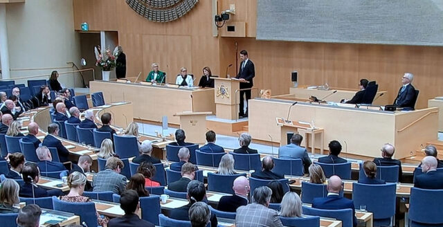 Översikt över riksdagens kammare med talarstol och ledamöter.